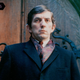Actor Jonathan Frid poses in a dark jacket in front of an ornate door.